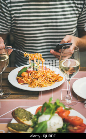 Italienisches Abendessen im Bistrot mit Caprese und Pasta mit Garnelen Stockfoto
