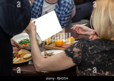 Die Menschen essen zusammen, beim Sitzen am Tisch. Weibliche Hand, White Paper, isoliert. Copyspace Stockfoto