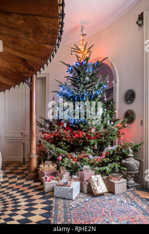 10 Fuß Weihnachtsbaum mit roten, weißen und blauen Lichtern geschmückt begrüßt die Gäste beim Betreten der Halle. Stockfoto