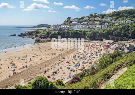 Besucher genießen die Sonne, Sand und Meer auf dem beliebten Strand von East Looe, Cornwall. Stockfoto