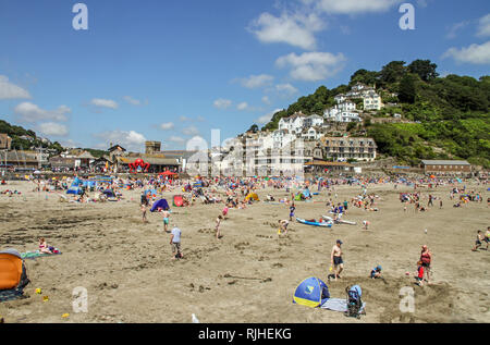 Besucher genießen die Sonne, Sand und Meer auf dem beliebten Strand von East Looe, Cornwall. Stockfoto