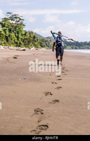 Ein Foto von einem Reiseleiter das Tragen von Brillen, die in der Entfernung auf den schönen Sandstrand von der abgeschiedenen Corcovado National Park, Costa Rica Stockfoto