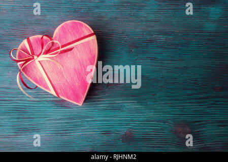 Herzförmige hölzerne Kiste auf Türkis im Hintergrund. Valentines Tag Konzept Stockfoto