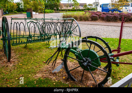 Renoviert und neu lackiert Landmaschinen ruht auf dem Gras unter anderen landwirtschaftlichen Werkzeuge in der Nähe der Schmiede in Gretna Green Stockfoto