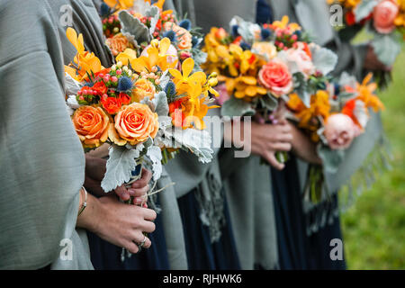 Brautjungfern ihre Hochzeit Blumensträuße Holding mit Gelb, Rot, Blau und Orange Blumen Stockfoto