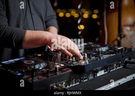 Dj-Mixe der Spur in der Diskothek an der Partei. Kopfhörer im Vordergrund und DJ Hände in Bewegung. Club Party DJ spielt live auf der Bühne im Nachtclub. Stockfoto