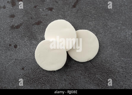 Blick von oben auf die drei weiße runde Süßigkeiten Wafer auf grauem Hintergrund mit natürlichem Licht beleuchtet. Stockfoto