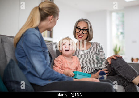 Junge Öffnung einen Geburtstag mit Großmutter und Mutter vorhanden Stockfoto