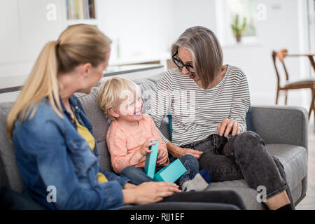 Junge Öffnung einen Geburtstag mit Großmutter und Mutter vorhanden Stockfoto