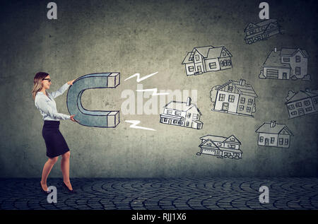 Immobilienmarkt Konzept. Geschäftsfrau mit einem Magnet für Haus und Haushalt stimmen Stockfoto