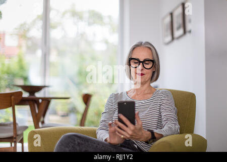 Reifen erwachsenen Weibchen mit einem Smartphone zu Hause Stockfoto