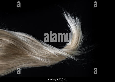 Blond glänzendes Haar auf Schwarz. Abstrakte Fashion Style Hintergrund. Stockfoto