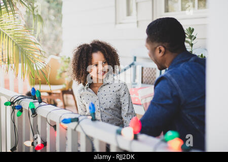 African American Vater und Tochter hängt Weihnachtsbeleuchtung im Freien Stockfoto
