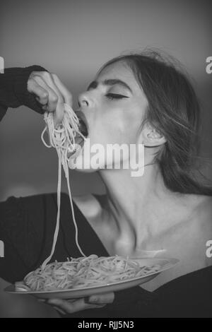 Hunger, Appetit, Rezept. Diät und gesunde Lebensmittel aus biologischem Anbau, Italien. Frau essen Pasta als Vorgeschmack oder Restaurant Kritiker. Koch Frau mit roten Lippen essen Pasta Stockfoto