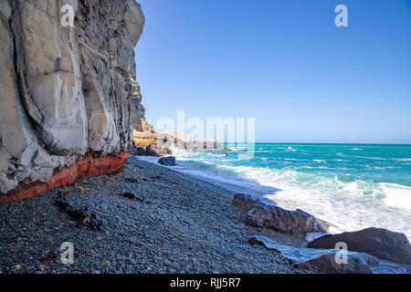 Ein schönes Aqua Meer trifft die Basaltfelsen bei Birdlings Flat, Canterbury, Neuseeland Stockfoto