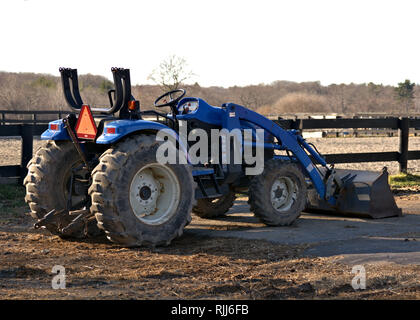 Ein blauer Bauernhof Traktor ist bereit für die Arbeit mit den Feldern, die im Hintergrund Stockfoto