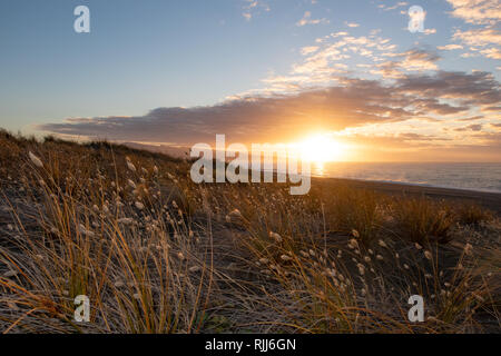 Die Sonne über dem Ozean und Kaitorete Spit Aufwärmen der Landschaft in Canterbury, Neuseeland Stockfoto