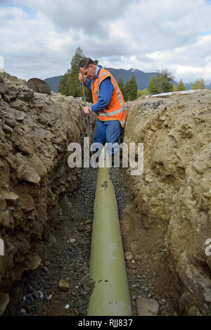 Ein Handwerker packt Kies unter ein Rohr in einen neuen Abfluss von Regenwasser Stockfoto