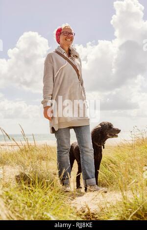 Frau geht mit ihrem Hund, König Pudel, in den Dünen am Meer, Denneville, Normandie, Frankreich Stockfoto