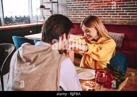 Romantische Vorschlag. Junger Mann küsst seine Freundin im Restaurant. Rote Rosen und Kerzen auf dem Tisch liegen in der Nähe der roten Wein. 7/8-pho Stockfoto