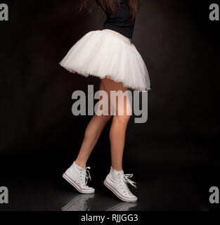 Weibliche Beine der Tänzer mit Tutu und Sneakers Schuhe im Studio Hintergrund Stockfoto