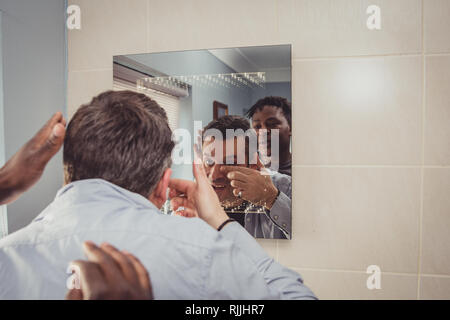 Ein homosexuelles Paar zusammen vor dem Badezimmerspiegel. Stockfoto