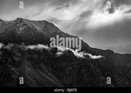 Die Anden in Schwarz und Weiß als Sonnenlicht die Gipfel und Wolken in der Nähe der Colca Canyon, Arequipa, Peru leuchtet auf. Stockfoto