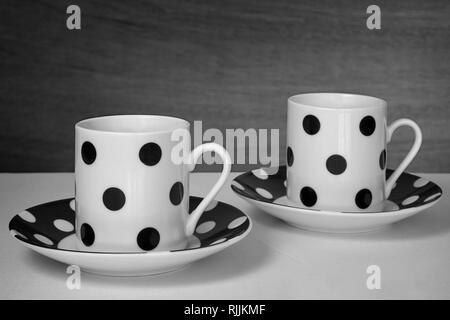 Zwei Tassen Kaffee mit schwarzen Tupfen und den weißen Hintergrund mit seiner Platte Stockfoto