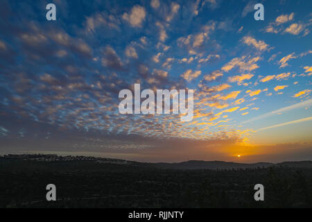 Die untergehende Sonne verleiht goldene Farbe auf den sich schnell bewegenden Wolken, über den Bergen in der Nähe von Jerusalem, Israel Stockfoto