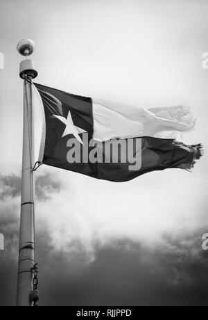 Ein tattered Texas State Flag Wellen auf den Mast gegen den Himmel in Schwarz und Weiß Stockfoto