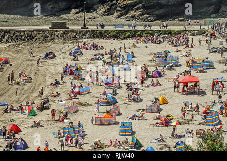 Besucher genießen die Sonne, Sand und Meer auf dem beliebten Strand von East Looe, Cornwall. Stockfoto