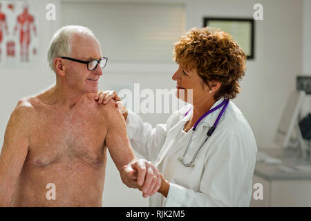 Lächelnd Arzt beruhigend einen älteren Patienten. Stockfoto