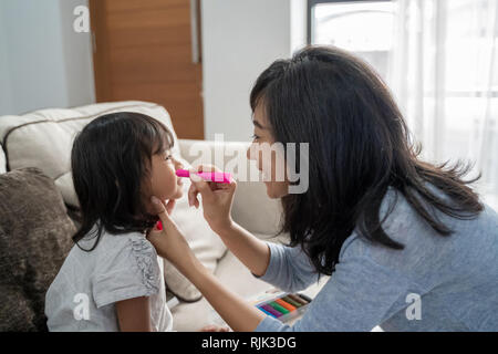 Asiatische Mutter Kinderschminken ihre kleine Tochter Stockfoto