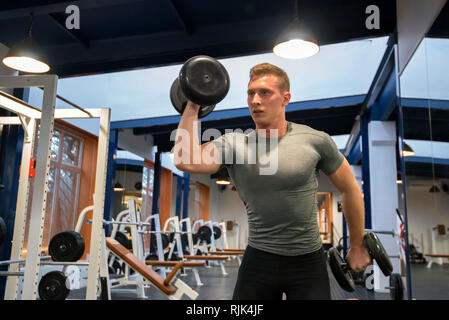 Portrait männlichen Athleten trainiert Bizeps in der Turnhalle Stockfoto