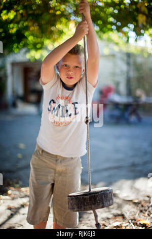 Porträt eines Jungen spielen auf einem Seil schwingen. Stockfoto