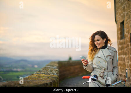 Junge Frau auf dem Fahrrad mit Ihrem Telefon. Stockfoto