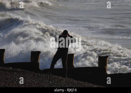 Hastings, East Sussex, UK. 07 Feb, 2019. UK Wetter: wechselhafter Witterung wie die Met Office Problem eine gelbe Warnmeldung für Wind im Südosten mit Gale force Winde erwartet heute und morgen. Ein Mann nimmt ein Bild von der rauen See. Credit: Paul Lawrenson 2019, Foto: Paul Lawrenson/Alamy leben Nachrichten Stockfoto