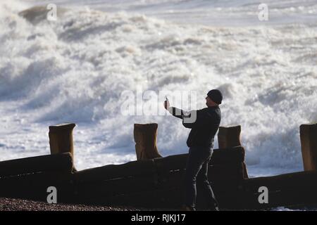 Hastings, East Sussex, UK. 07 Feb, 2019. UK Wetter: wechselhafter Witterung wie die Met Office Problem eine gelbe Warnmeldung für Wind im Südosten mit Gale force Winde erwartet heute und morgen. Ein Mann nimmt ein Bild von der rauen See. Credit: Paul Lawrenson 2019, Foto: Paul Lawrenson/Alamy leben Nachrichten Stockfoto