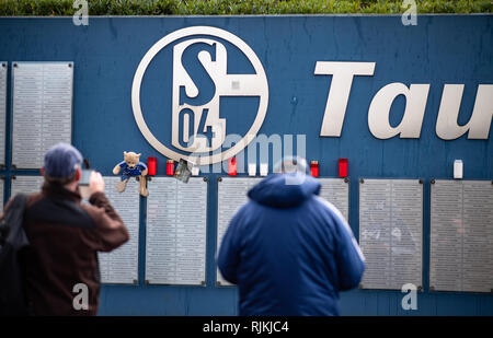 Gelsenkirchen, Deutschland. 07 Feb, 2019. Zwei Fans des FC Schalke 04 stehen an der Wand die tausend Freunde' vor der Veltins Arena, wo Fans bereits in Trauer Kerzen. Rudi Assauer, ehemaliger Manager des FC Schalke 04, am Mittwoch gestorben (06.02.2019) im Alter von 74 Jahren. Credit: Guido Kirchner/dpa/Alamy leben Nachrichten Stockfoto