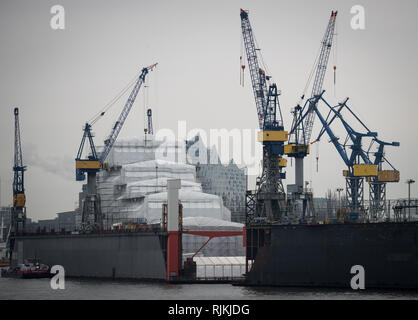 Hamburg, Deutschland. 07 Feb, 2019. Die Silhouette der Elbphilharmonie kann hinter einem Schiff durch Planen in schwimmenden Dock 10 von Blohm Voss geschützt angesehen werden. Credit: Christian Charisius/dpa/Alamy leben Nachrichten Stockfoto