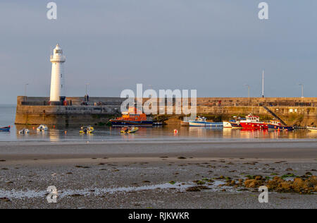 Hafen Leuchtturm und Boote im Hafen bei Ebbe an sonnigen Abend. Donaghadee Hafen, County Down, Nordirland. Stockfoto