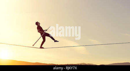 Ropewalker in schwarzen Hut wandern Seil hoch in den Himmel. Mixed Media Stockfoto