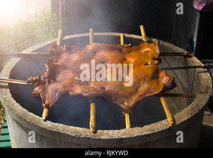 Grill das Schwein mit einem Grillen auf dem Grill. Gegrillte traditionelle Kohle und Feuer. Stockfoto