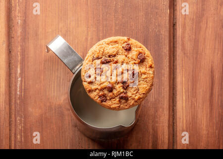 Guten Morgen. Eine Chocolate Chip Cookie, Schuß von oben auf einem milchkännchen, auf einem dunklen rustikalen Holztisch mit einem Platz für Text Stockfoto