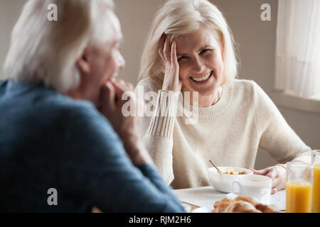 Grauhaariger senior Paar lachend Sitzen am Tisch Stockfoto