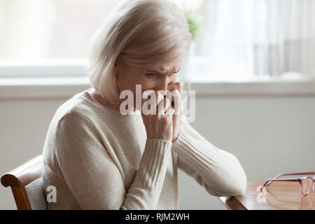 Frau mittleren Alters am Tisch sitzen Schreien Stockfoto