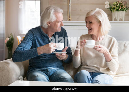 Lächelnde Paare im mittleren Alter Menschen sitzen auf der Couch Tee trinken. Stockfoto