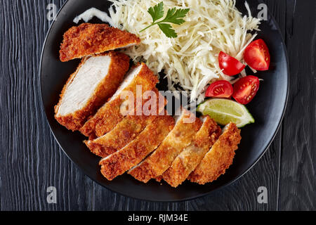 Tonkatsu - panko Panierte frittierte Schweinekotelett. Frittierte Schweinelende Schnitzel mit frischen Kohl Salat, Tomaten und Limettensaft, Scheiben, japanische Küche, Fla Stockfoto