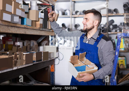 Lächelnd mann Arbeiter Sortierung Sanitärtechnik Details in der Werkstatt Stockfoto