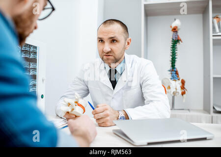 Porträt eines leitenden Therapeuten während der medizinischen Beratung, anatomische Modell der Wirbelkörper im Büro Stockfoto